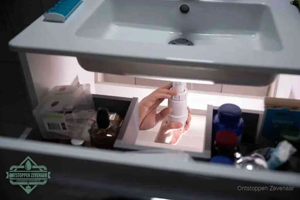 Een pompfles met zeep boven een wastafel, de heet water en afwasmiddel-methode om een vetprop in de afvoer los te maken in Zevenaar