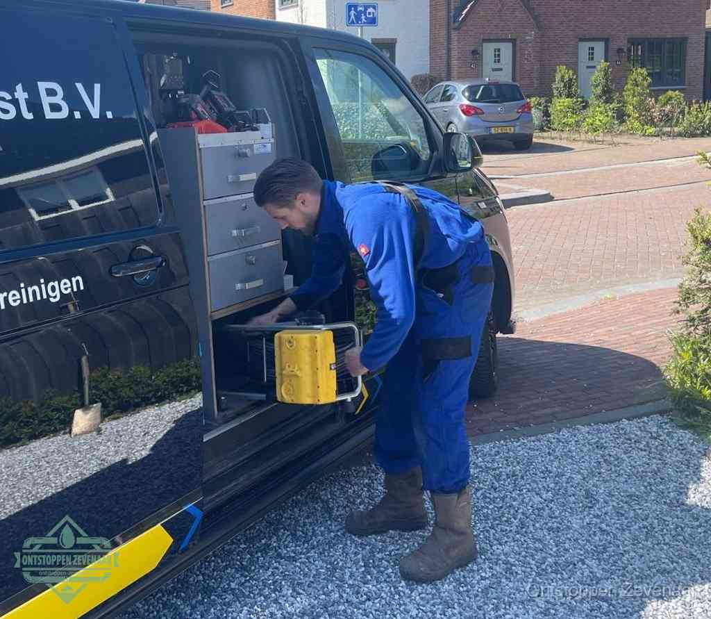 Een monteur pakt buiten op de oprit gereedschap uit de bedrijfsbus, het moment om een professional in te schakelen voor een verstopte afvoer in Zevenaar