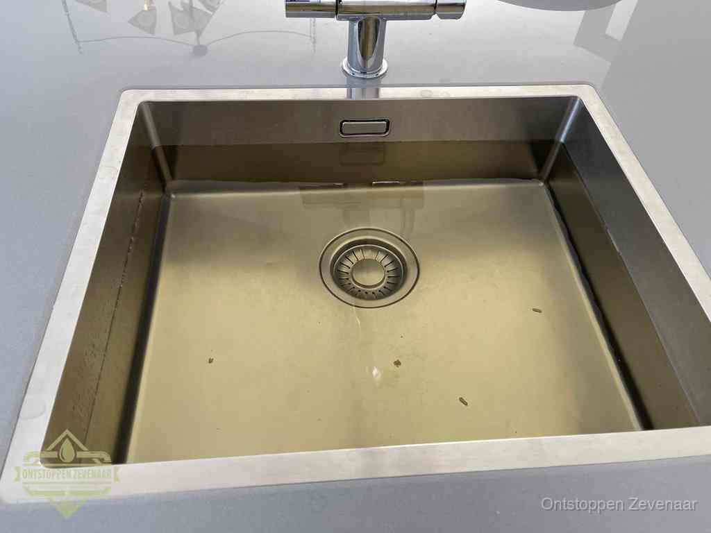 Stilstaand water in een rvs spoelbak dat niet wegloopt, een duidelijk signaal van een gootsteenverstopping in Zevenaar