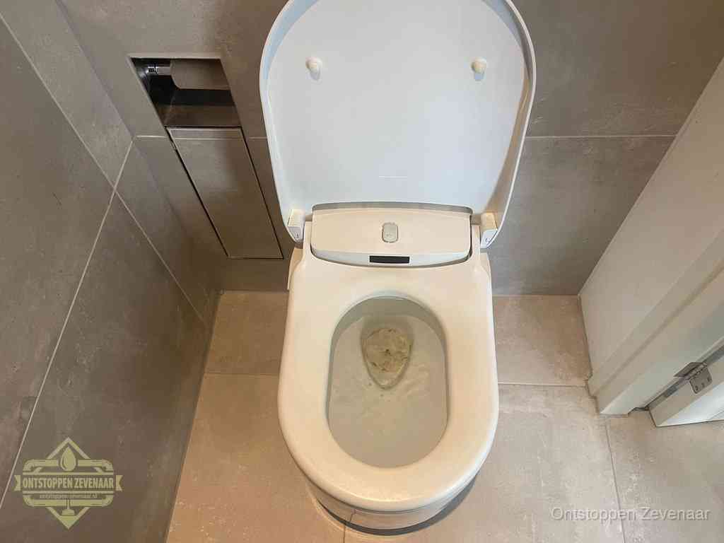 Een wit hangtoilet waarin een prop wc-papier op het water blijft drijven, een duidelijk signaal van een verstopte wc in Zevenaar
