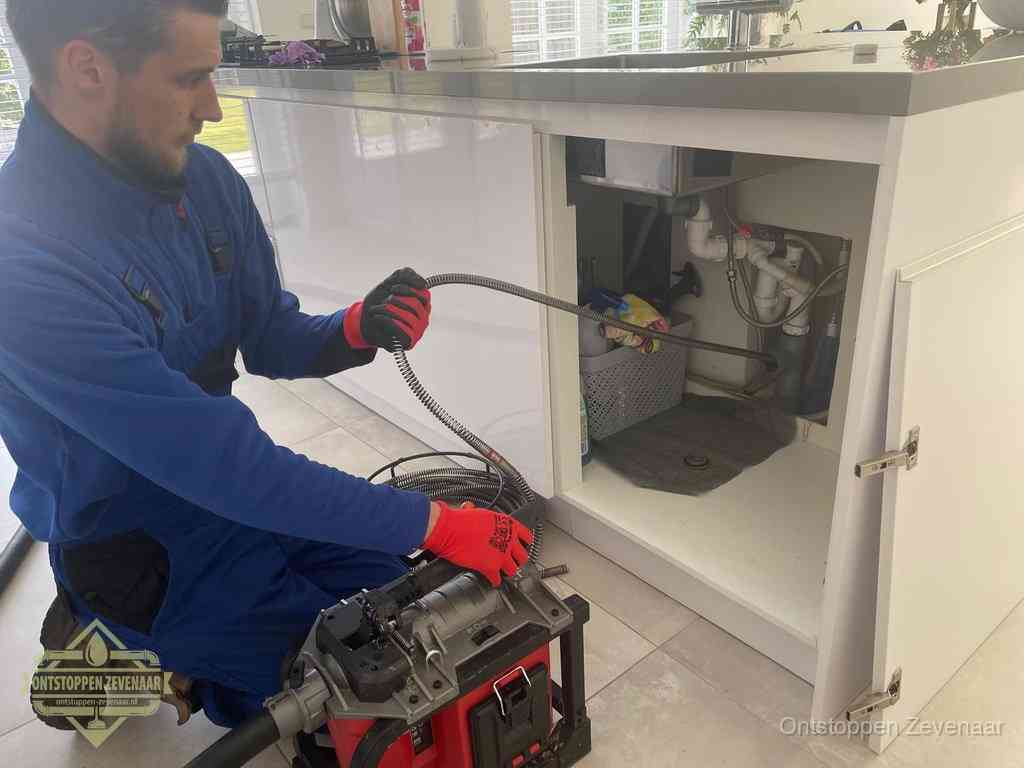 Een monteur reinigt de keukenafvoer grondig met een veermachine om terugkerende gootsteenverstoppingen te voorkomen in Zevenaar
