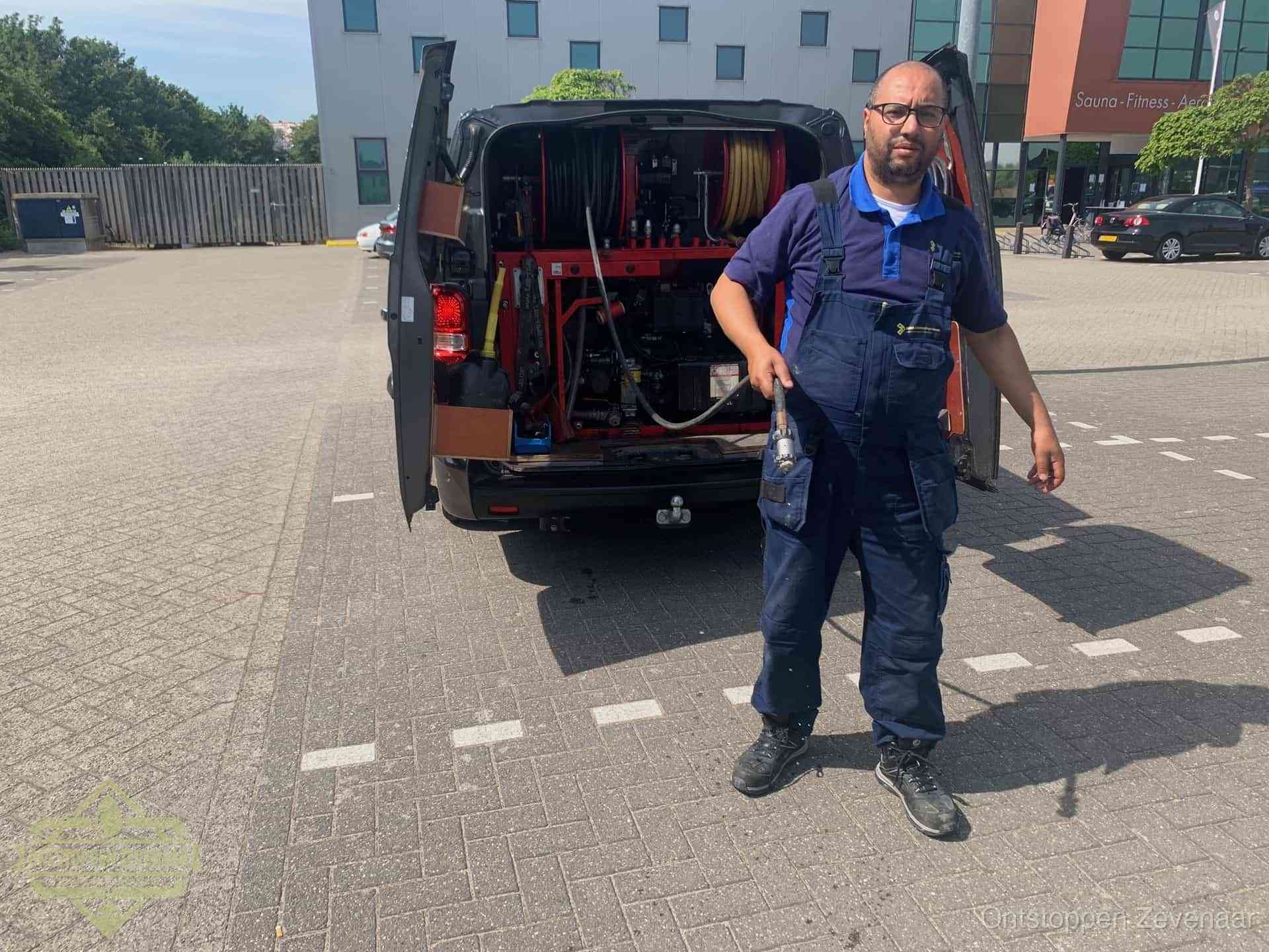 Een monteur bij zijn bestelbus met een hogedruk- en rioolreinigingsunit, klaar om de oorzaak van terugkerende wc-verstoppingen aan te pakken in Zevenaar