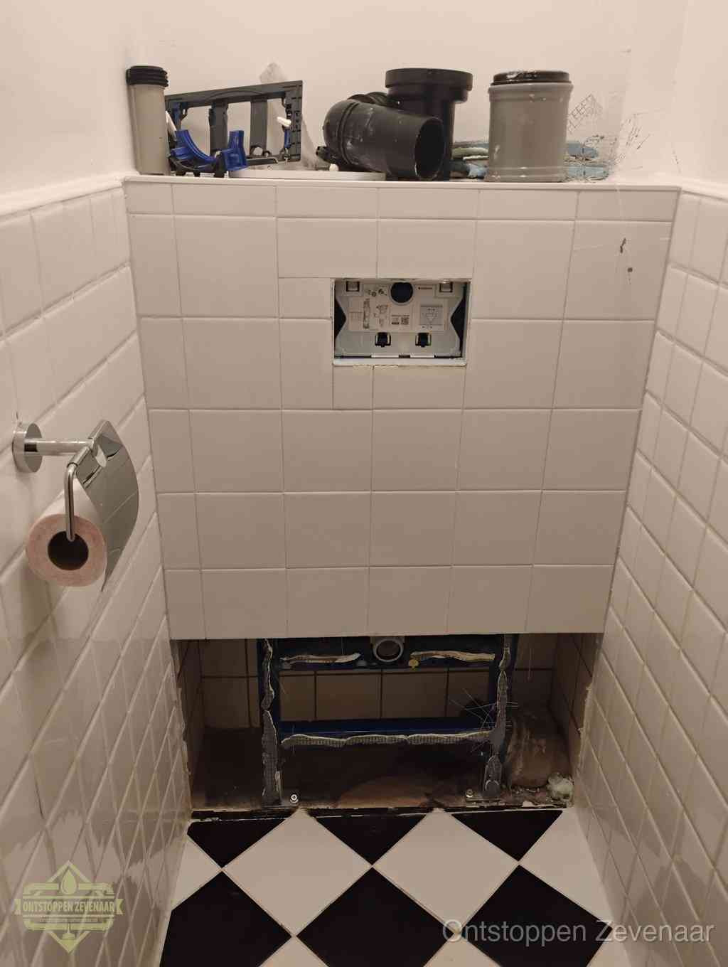 Een toiletruimte waar het hangtoilet en de inbouwreservoir-onderdelen zijn vrijgelegd voor onderhoud, periodiek nazicht voorkomt een wc-verstopping in Zevenaar